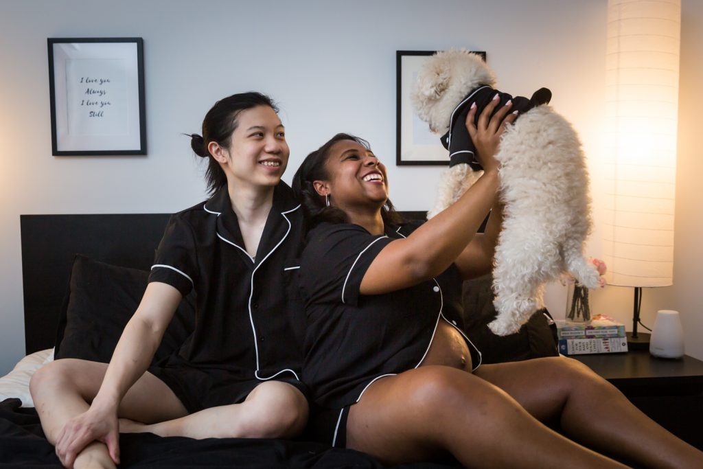 Couple on bed holding up dog for an article on indoor maternity photo shoot tips