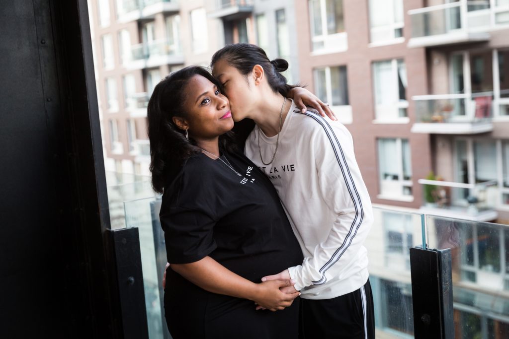 Man kissing pregnant woman on terrace for an article on indoor maternity photo shoot tips