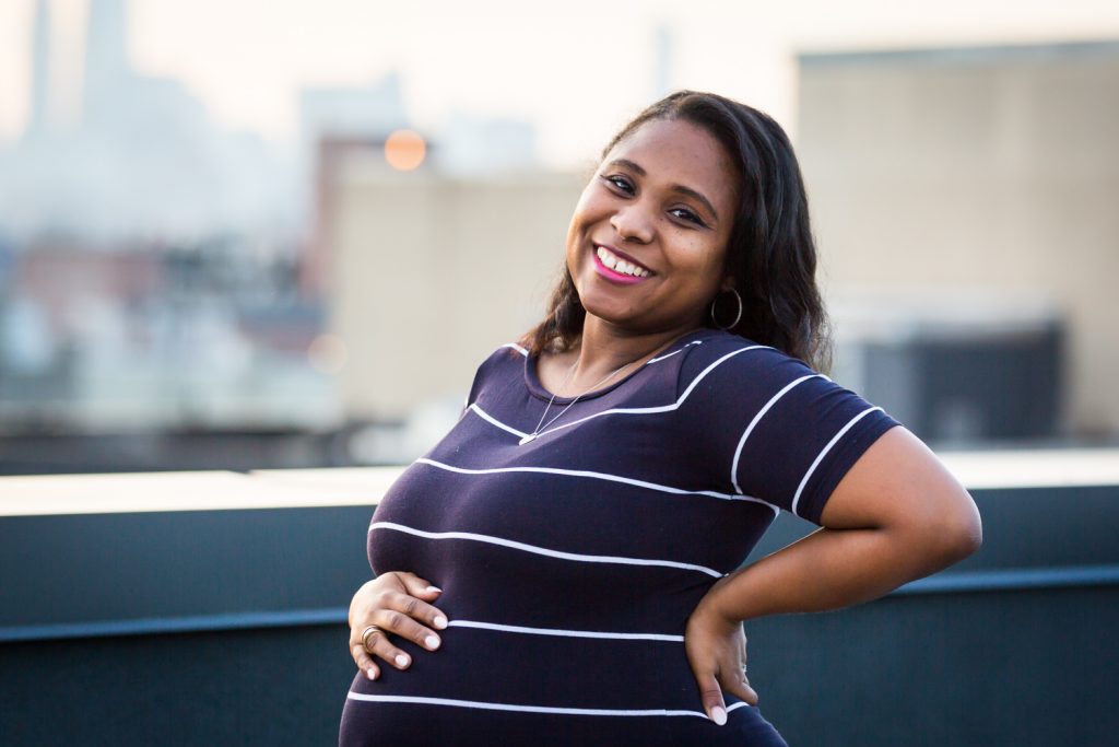 Smiling African American pregnant woman with hand on back
