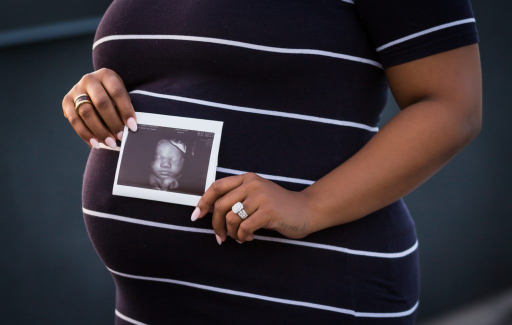 Close up of African American pregnant woman holding ultrasound photo