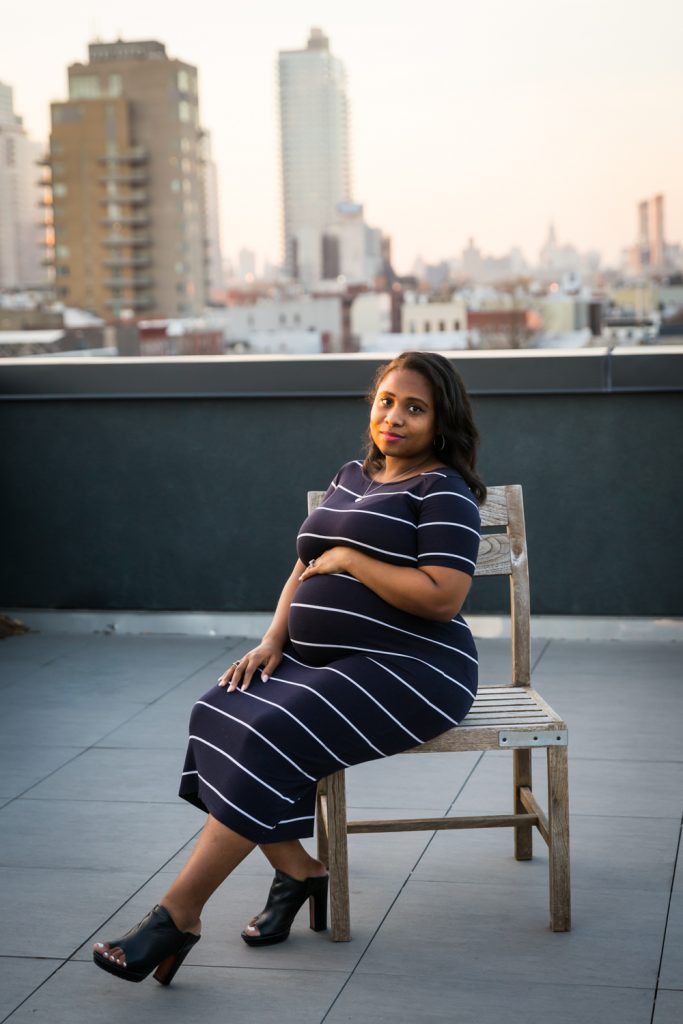 African American pregnant woman sitting on chair on roof