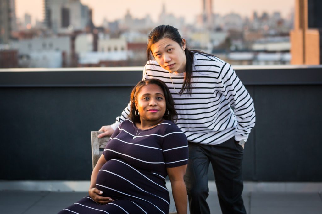Couple posed on chair on roof during maternity portrait photo shoot