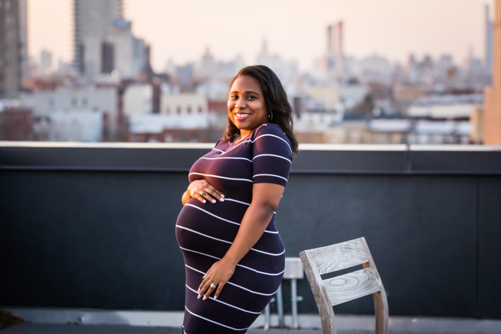 Pregnant woman beside chair on Brooklyn rooftop