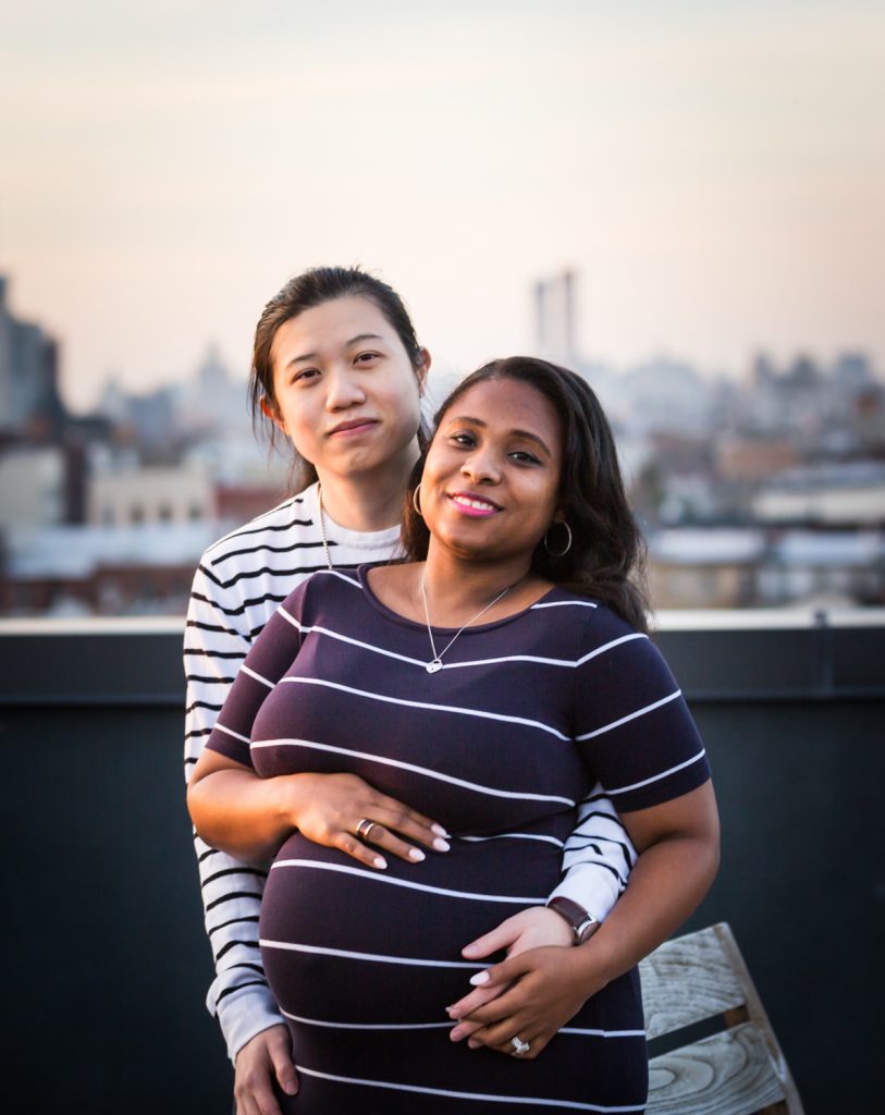 Couple hugging on Brooklyn rooftop during maternity portrait photo shoot