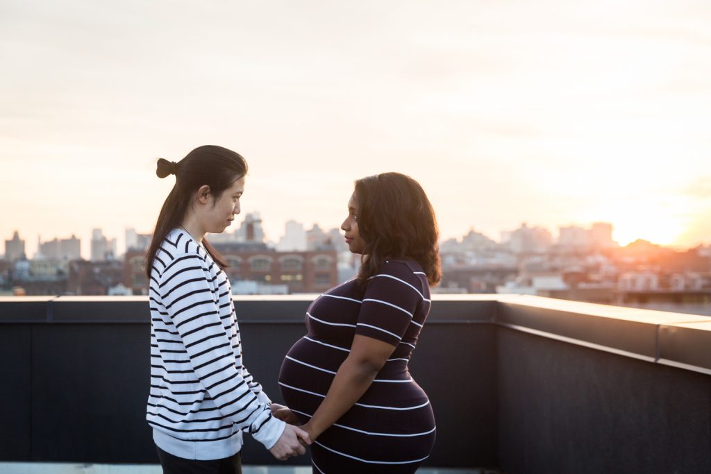 Couple holding hands and looking at each other during maternity portrait photo shoot