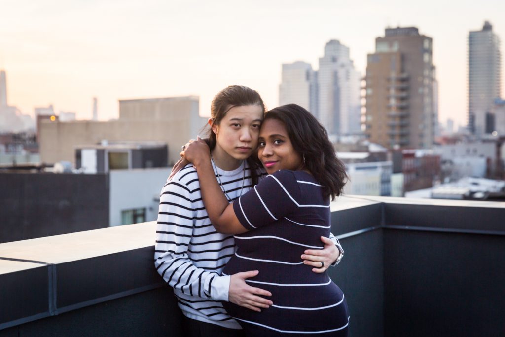 Pregnant woman hugging husband on Brooklyn rooftop