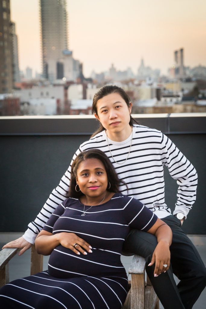 Couple looking into camera on Brooklyn rooftop during maternity portrait photo shoot
