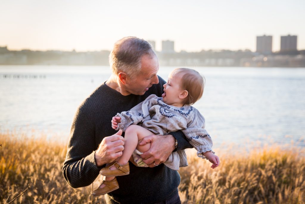 Father holding little girl in Riverside Park with Hudson River behind