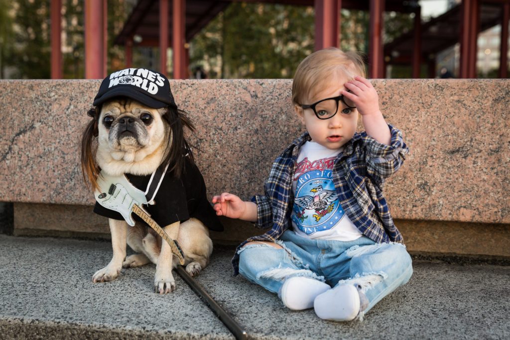 Little girl holding glasses with dog while dressed in Halloween costume