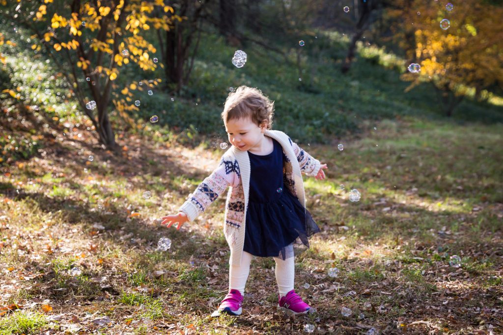 Little girl chasing bubbles in Riverside Park