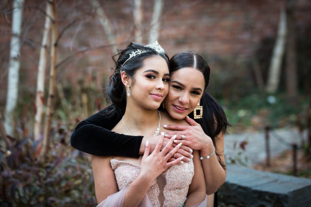 Mother and daughter hugging Girl wearing tiara and coat with fur hood for an article on cold weather portrait tips
