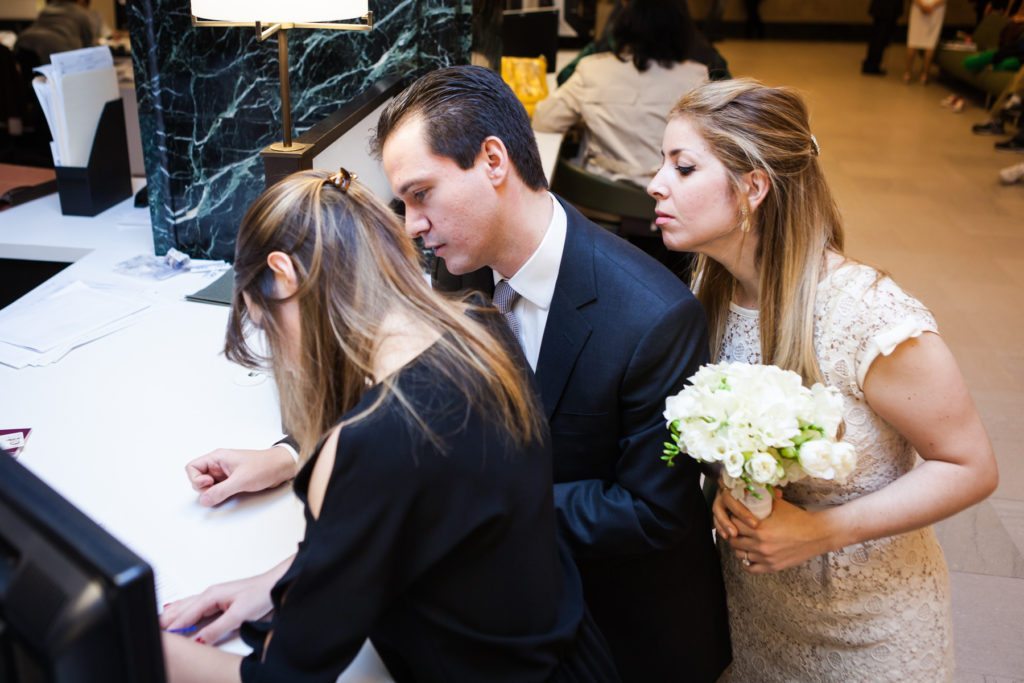 Filling out paperwork at a Manhattan Marriage Bureau wedding, by NYC wedding photojournalist, Kelly Williams