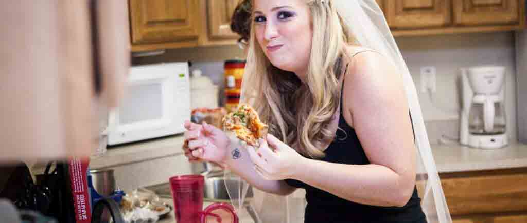 Bride wearing veil and eating pizza before her Fort Hamilton Community Club wedding