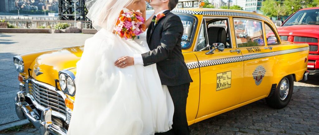 Groom kissing bride on top of old NYC taxicab before a Ravel Hotel Penthouse wedding