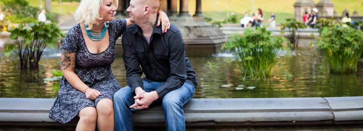 Central Park engagement photos of couple sitting on the side of Bethesda Fountain