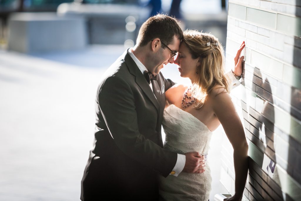 Groom and bride touching foreheads against wall at a trash the dress shoot