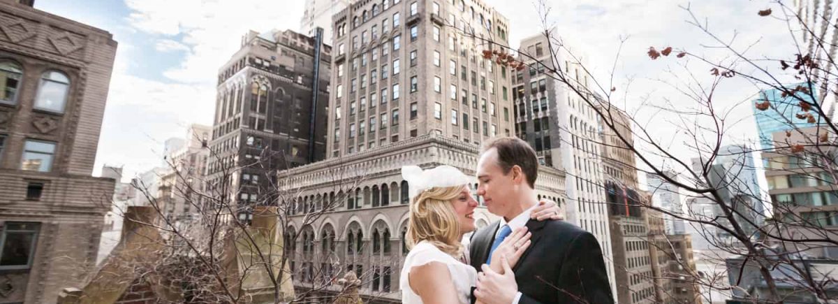 Couple hugging with NYC skyline in background before a Library Hotel wedding