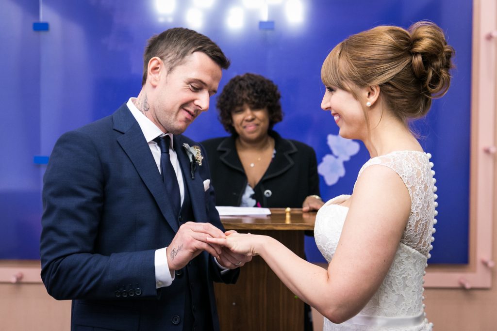 NYC City Hall wedding photos of groom putting ring on bride's finger