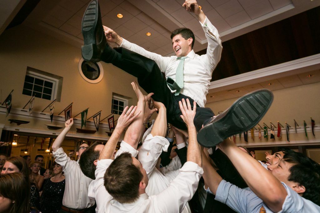Groom thrown in the air by guests on the dance floor at an American Yacht Club wedding