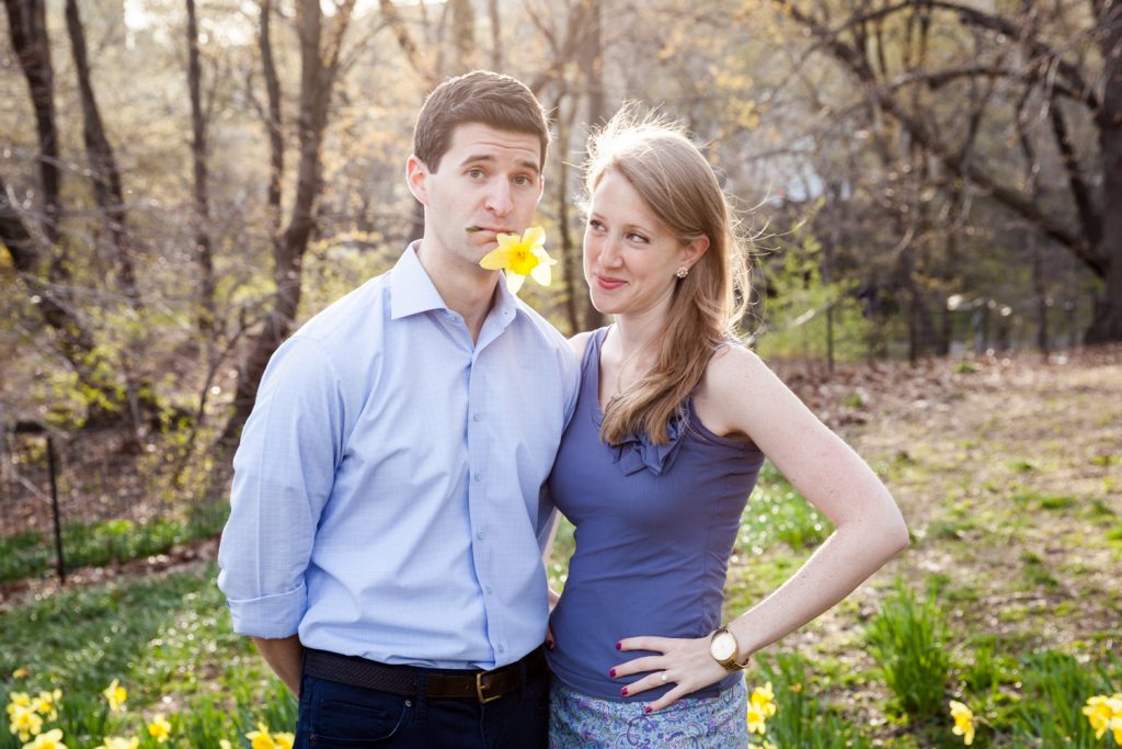 Man with daffodil in mouth next to woman during a Central Park engagement session