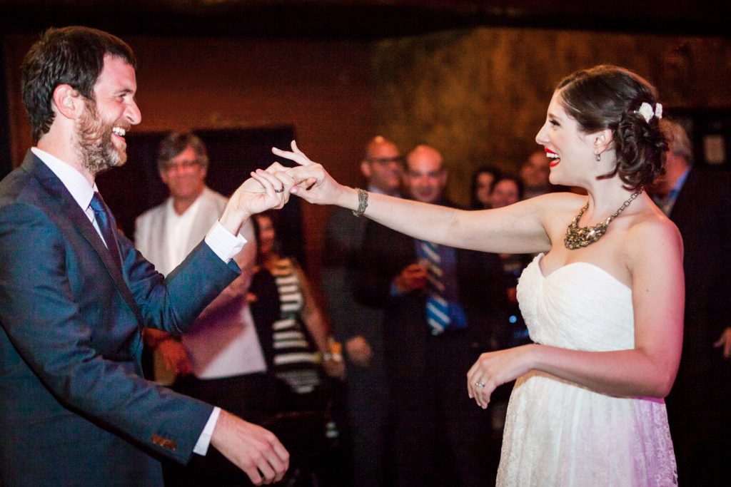 Bride and groom holding hands during first dance at a Bell House wedding anniversary party