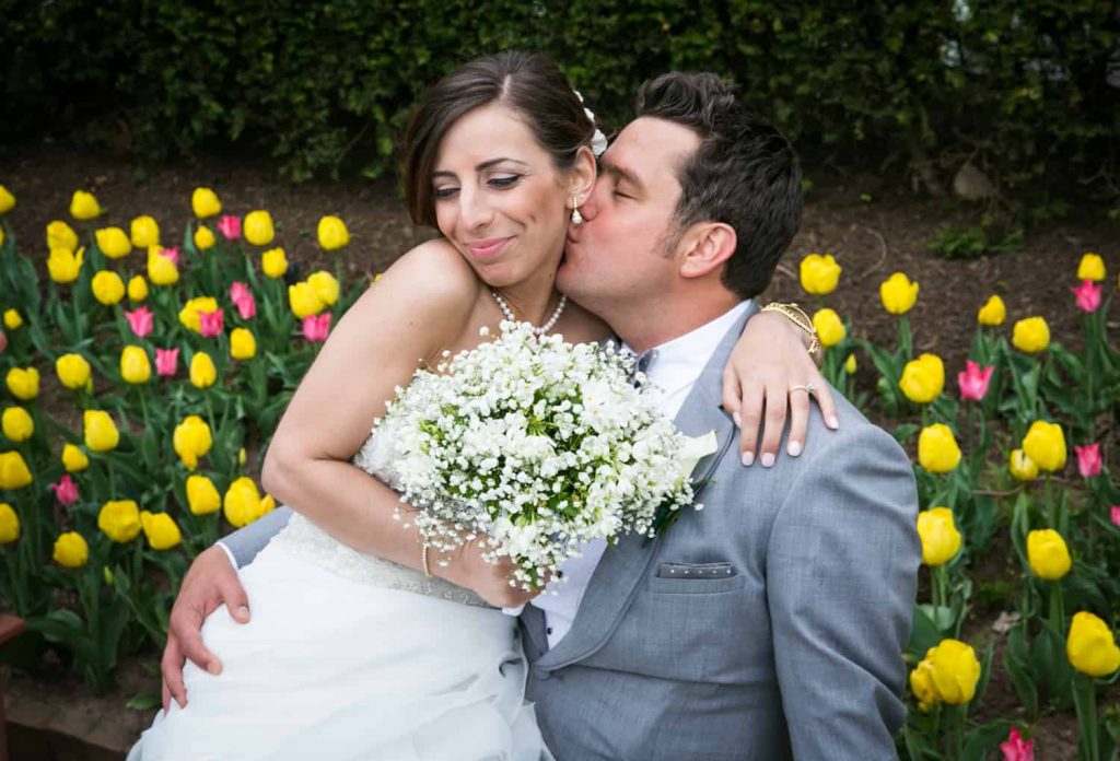 Groom kissing bride on cheek for an article called 'Do you need a second photographer?'
