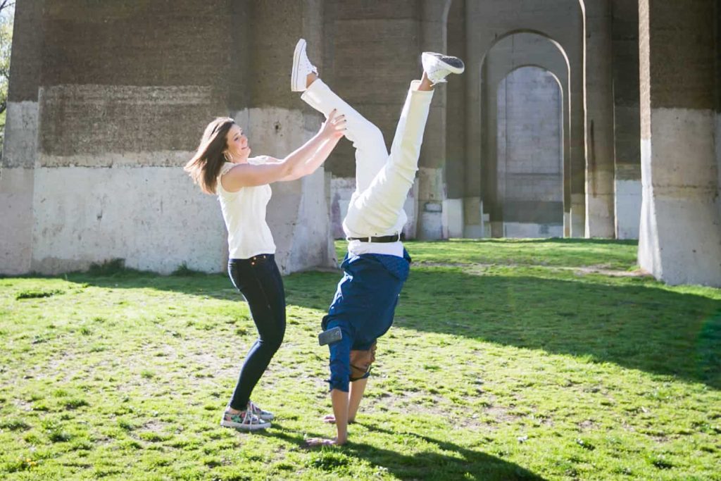 Woman holding man's legs during an Astoria Park engagement shoot