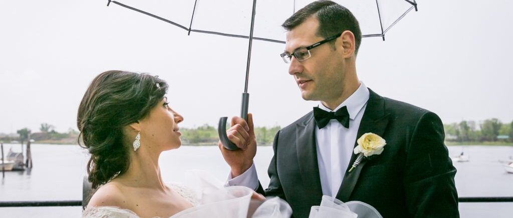 Groom holding clear umbrella over bride for an article on NYC rainy day photo tips