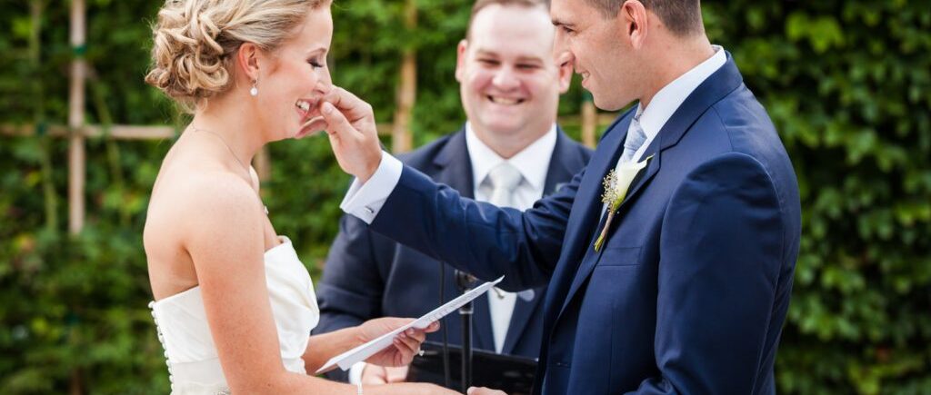 Groom wiping tear from bride's face during ceremony for an article on how to become a wedding officiant in NYC