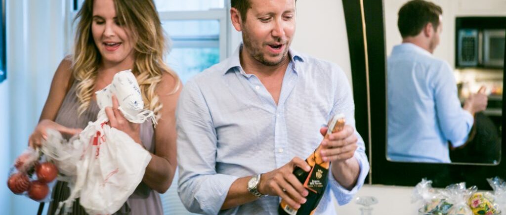 Man opening bottle of champagne at a NYC rehearsal dinner in a Manhattan apartment