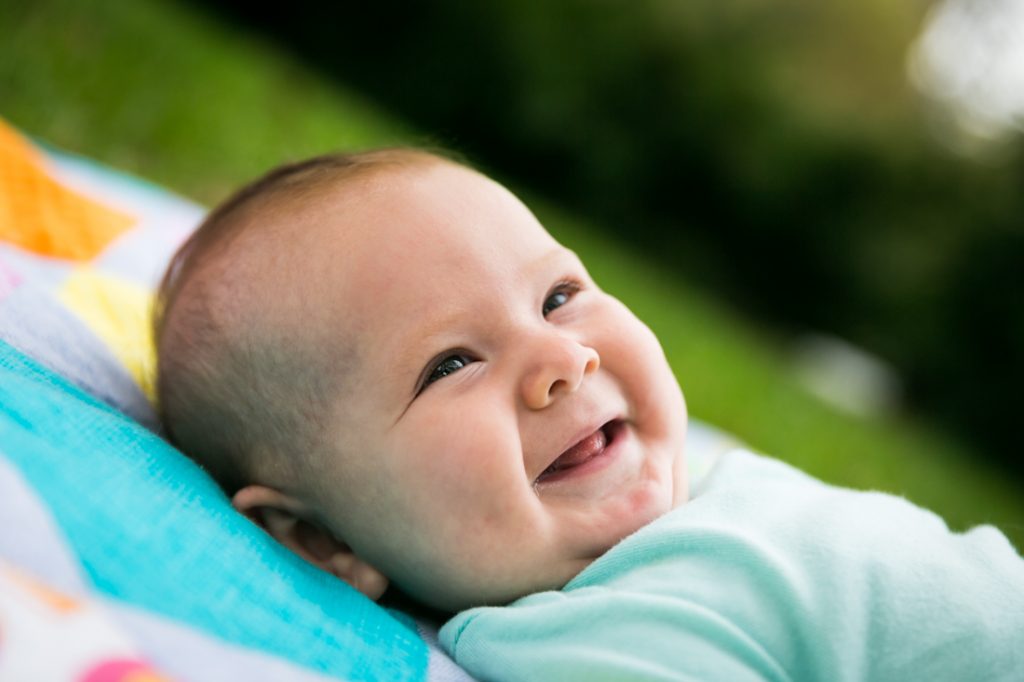 Smiling baby on quilt by Brooklyn baby photographer, Kelly Williams