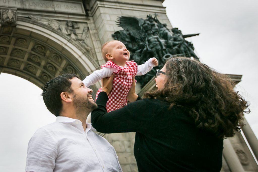 Parents lifting up little girl under Grand Army Plaza arch