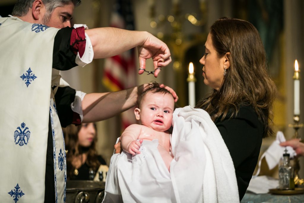 Baby getting hair cut during baptism by NYC Greek orthodox baptism photographer, Kelly Williams