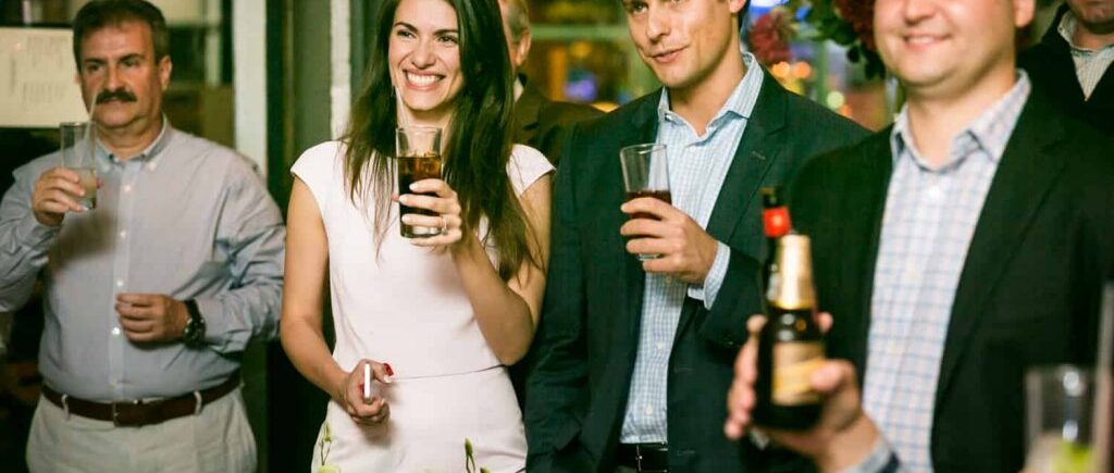 Couple and guests holding drinks for an article on rehearsal dinner tips