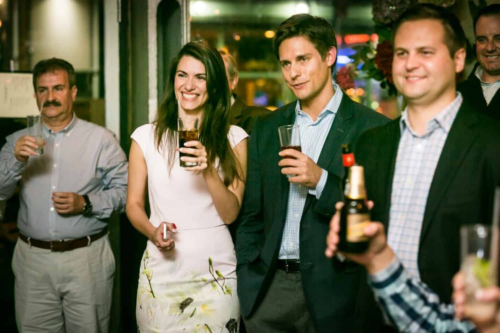 Couple and guests holding drinks for an article on rehearsal dinner tips