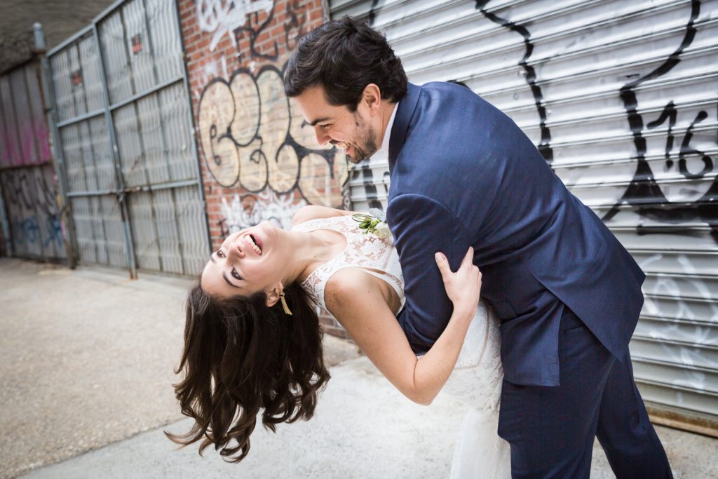 Groom dipping bride with graffiti background before a Wythe Hotel wedding