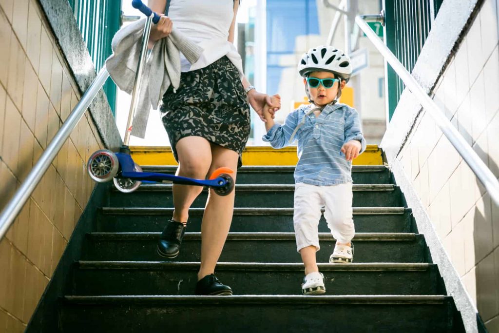 Little boy wearing sunglasses and helmet walking down stairs during a day in the life photography session
