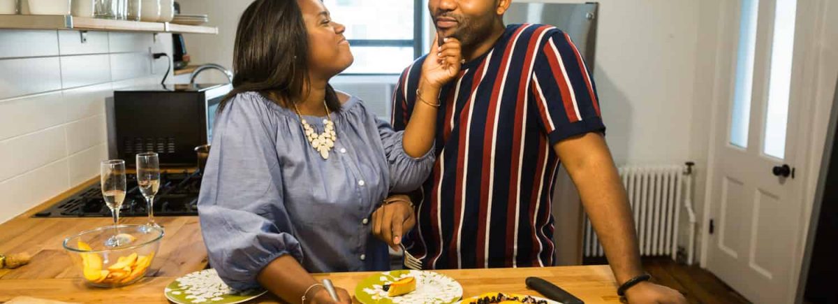 Woman touching man's face in kitchen for an article on creative engagement photo shoot ideas