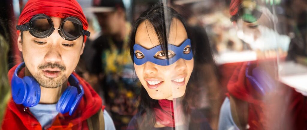 Couple in a mirror dressed as Spiderman and Supergirl for a Comic Con engagement shoot