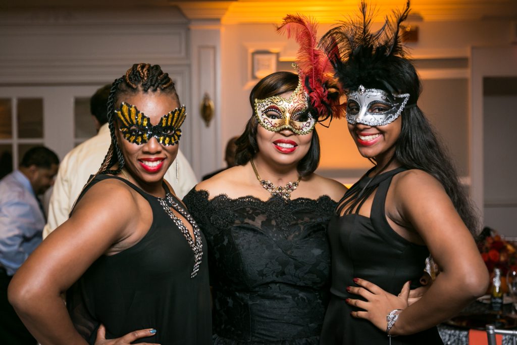 Three women dressed in masks for an article on how to plan a Halloween wedding