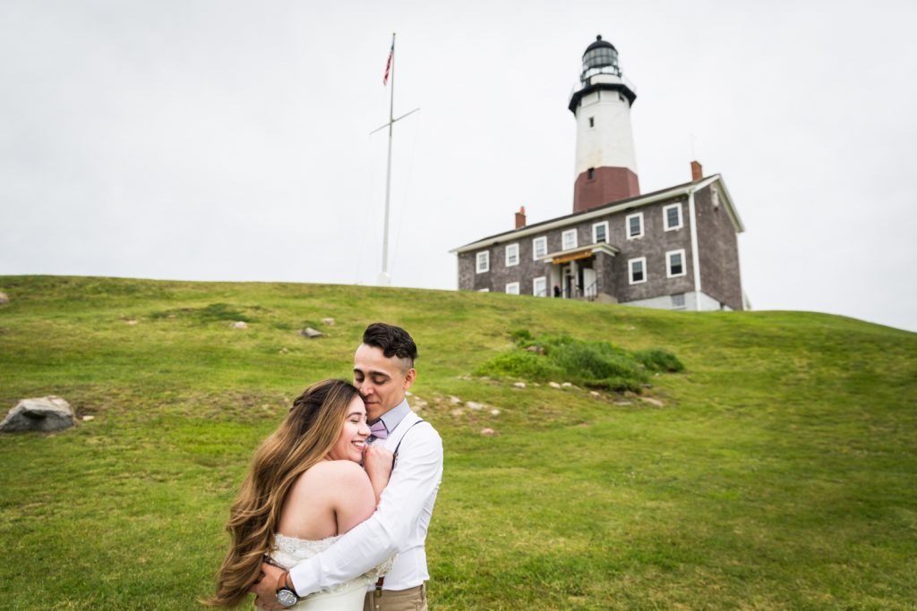 Bride and groom hugging in front of Montauk Lighthouse for an article on Montauk Lighthouse Wedding Tips