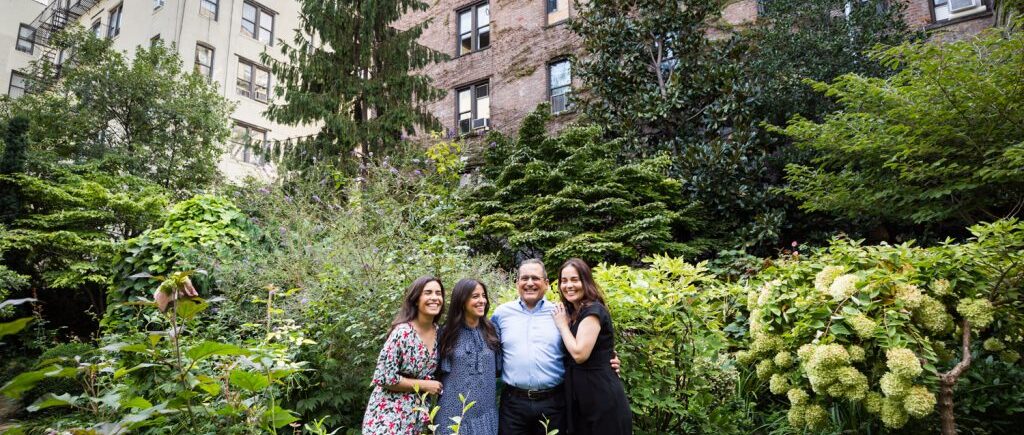 Family in middle of garden with apartment building in background at a community garden family portrait session