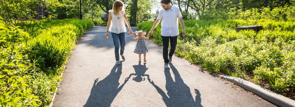 Parents holding hands with little girl in Forest Park for an article on toddler portrait tips