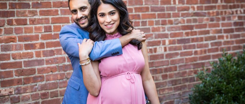 Portrait of pregnant woman and her husband with his arm around her shoulders for article on maternity portrait tips