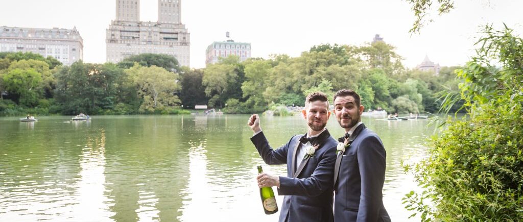 Two grooms popping open a bottle of champagne for an article entitled, ‘Do you need a permit to get married in Central Park?’