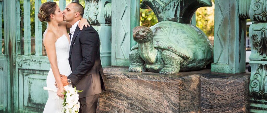 Bride and groom kissing by Southern Boulevard gate turtle for an article on Bronx Zoo wedding venue updates