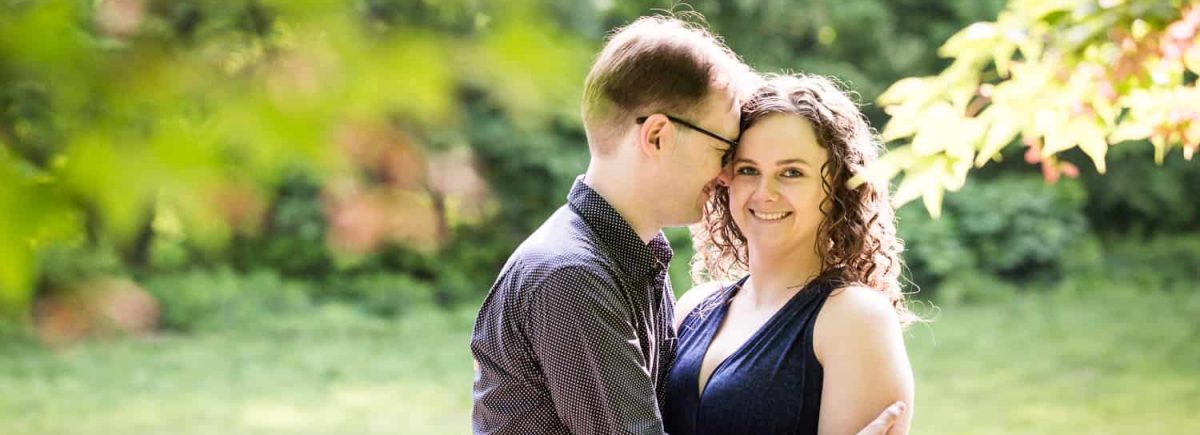 Couple cuddling in Central Park for Shakespeare Garden engagement photos