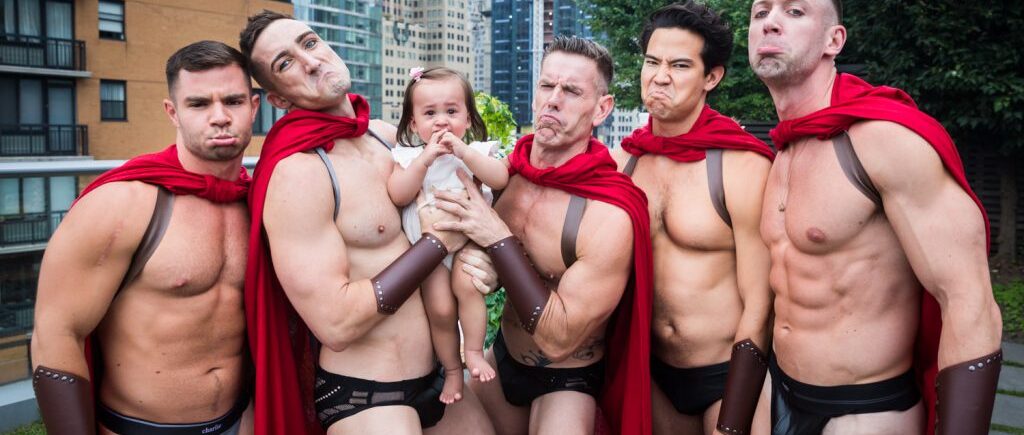 Birthday party photography of scantily clad men dressed as gladiators surrounding a little baby