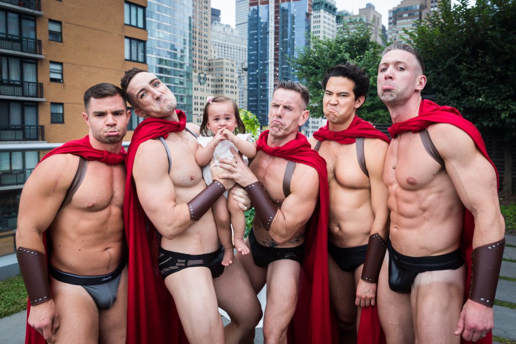 Birthday party photography of scantily clad men dressed as gladiators surrounding a little baby