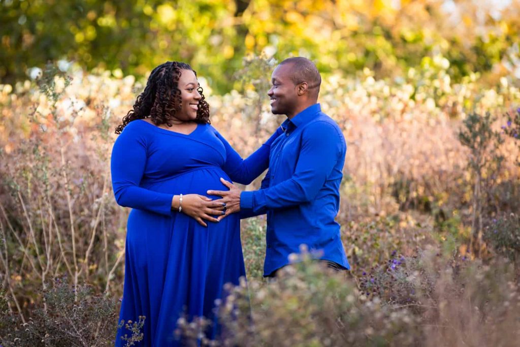 African American couple standing in Forest Park for an article on maternity photo shoot ideas
